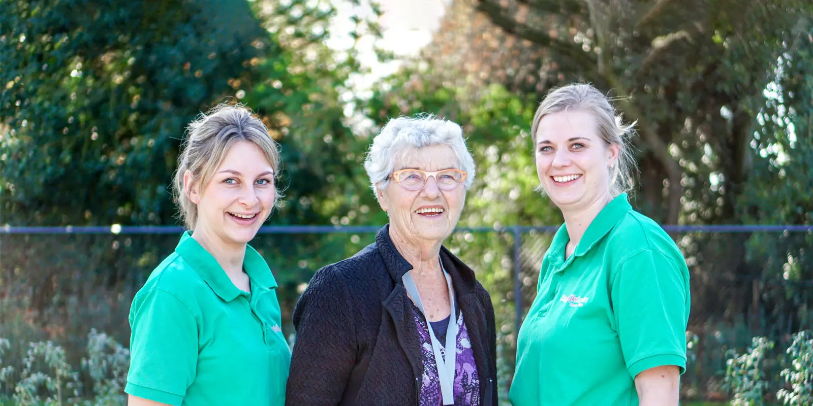 twee collega's en een bewoonster lachen vriendelijk naar de camera