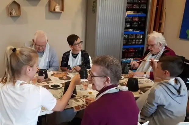 Bewoners van Het Drostenhuis knutselen samen aan tafel met de leerlingen