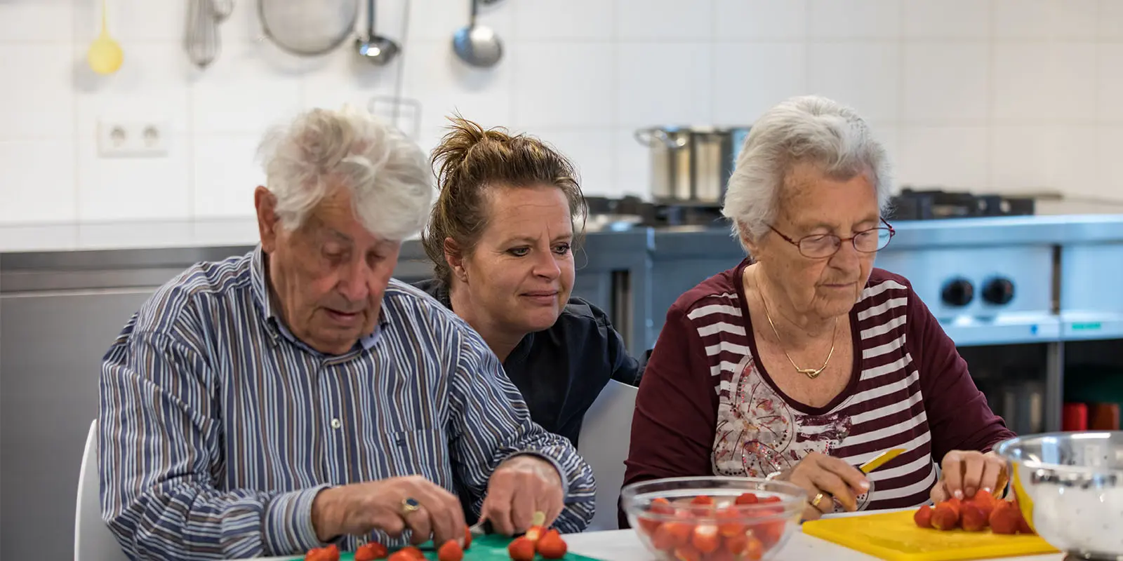 Samen met twee bewoners kookt Anja als Kok het eten. De bewoners snijden de groenten voor haar.