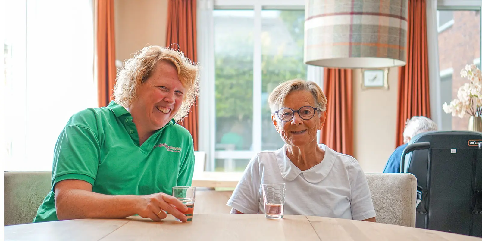 Een bewoonster met dementie bij Dagelijks Leven drinkt samen een kopje thee met een medewerker