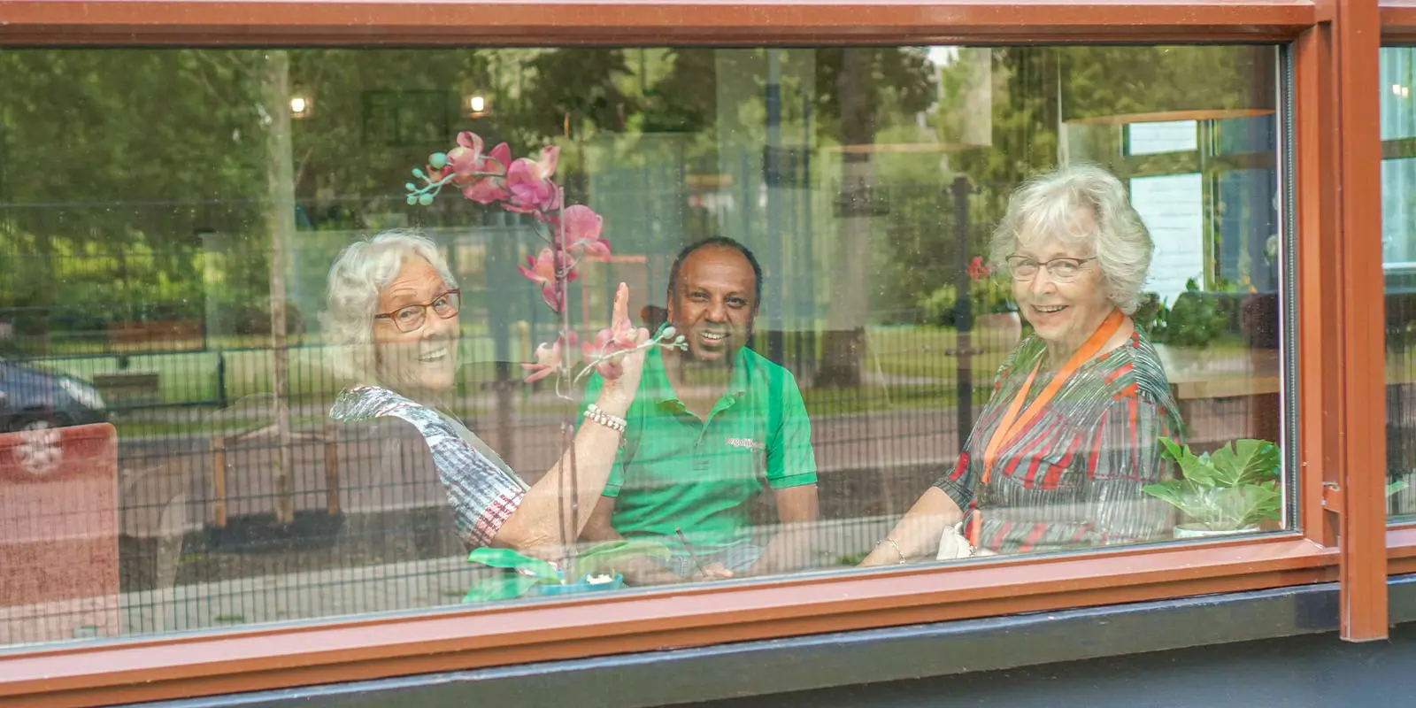 Bewoners zwaaien vrolijk achter een raam