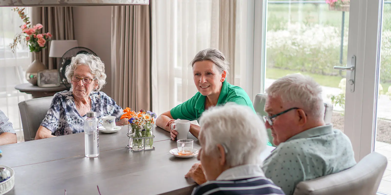 Bewoners aan tafel samen met een medewerker