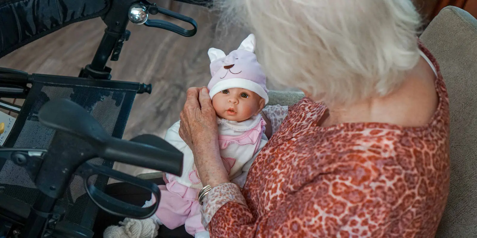 Een mevrouw met dementie heeft een babypop vast en verzorgt haar als een echte baby