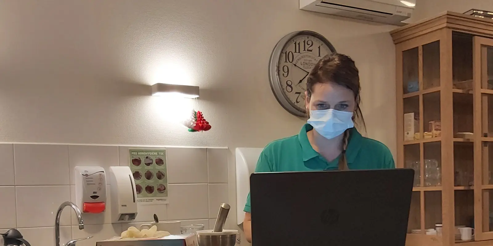 Verzorgende Isabel aan het werk bij Dagelijks Leven. Ze staat achter een laptop.