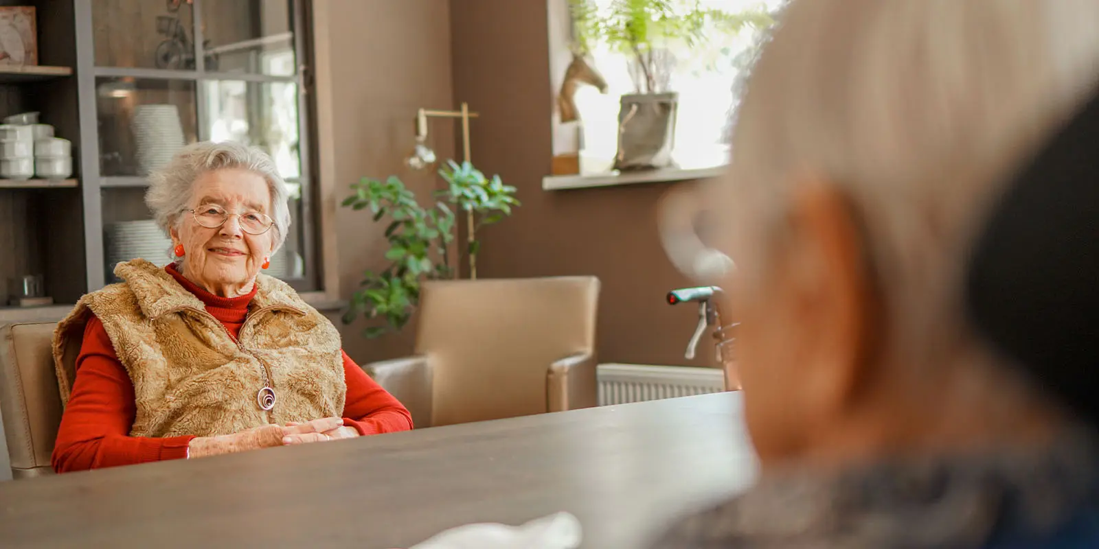 Een bewoonster zit aan tafel nadat ze ervoor heeft gekozen zich in te schrijven om te wonen bij Dagelijks Leven