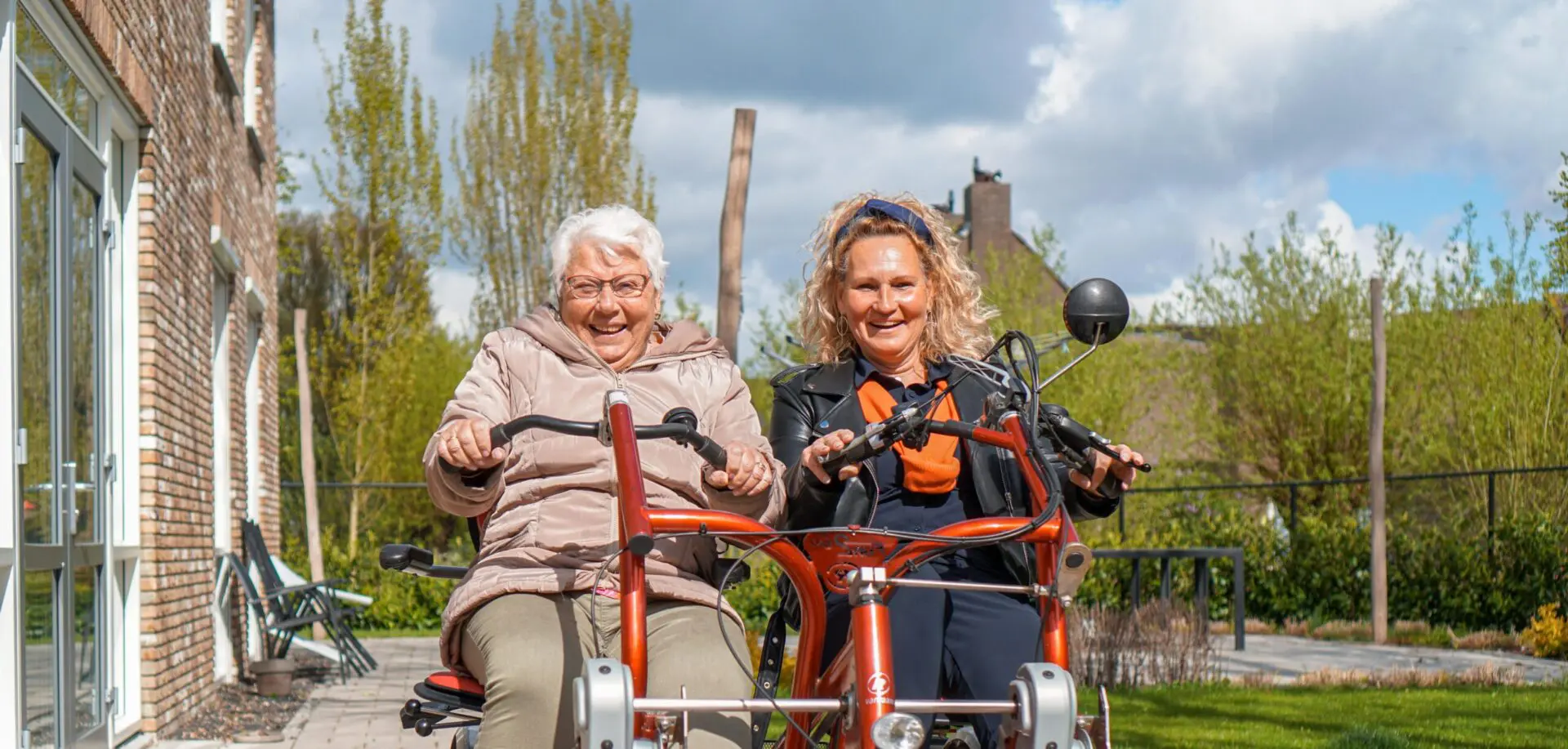 Bewoonster en verwanten fietsen samen in de tuin van Het Abtswoudehuis