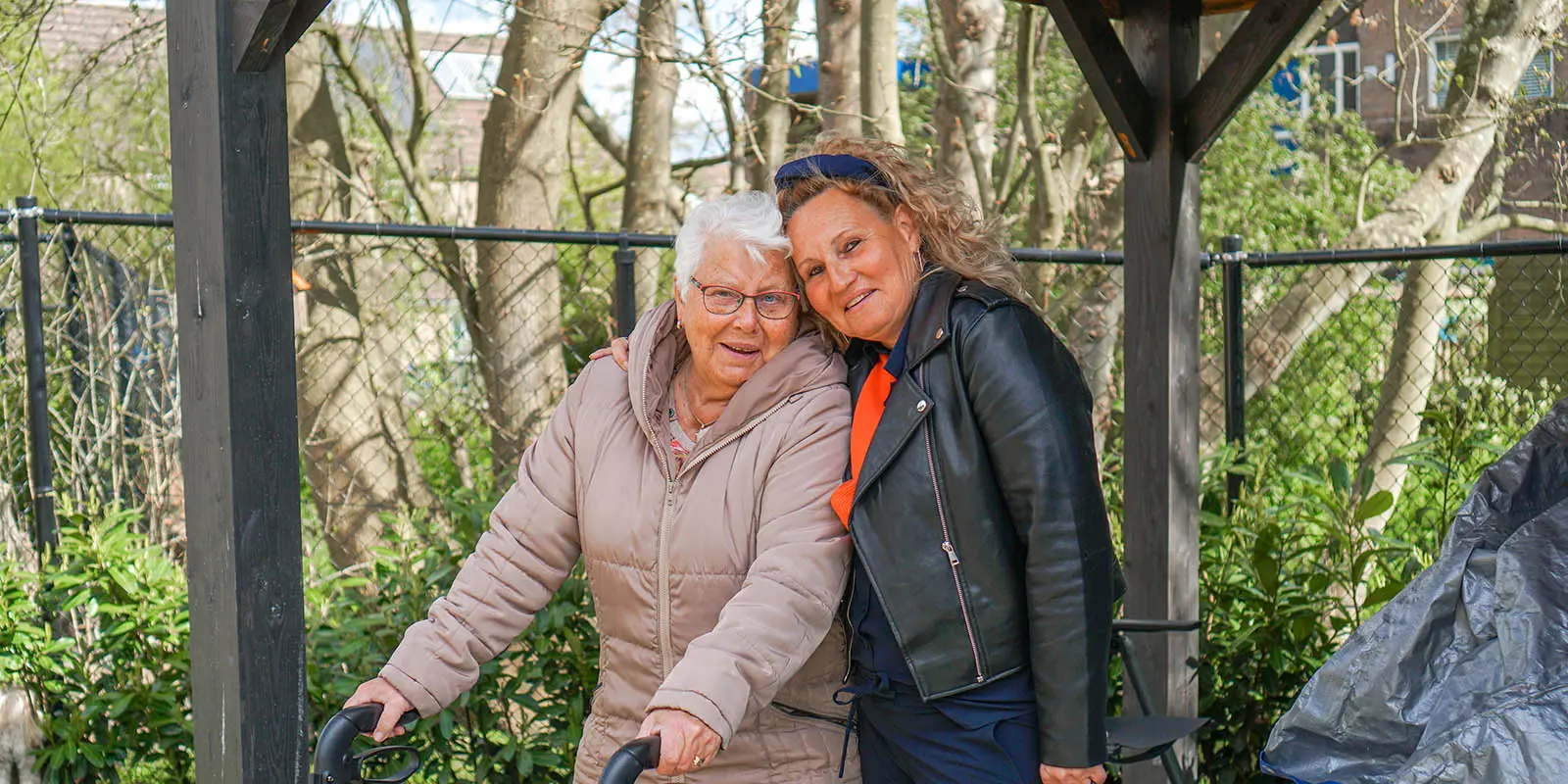 Bewoner staat samen met haar verwant in de tuin van een locatie bij Dagelijks Leven