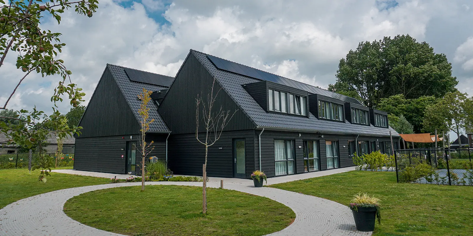 Bewoners wandelen zelfstandig door de open poort naar de buurt, in een veilige, dementievriendelijke omgeving in Heerhugowaard.