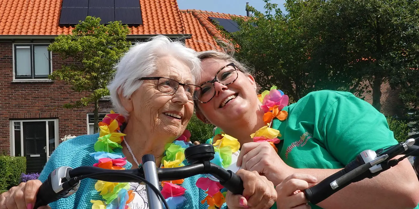 Verpleegkundige Kelly samen met een bewoner met dementie op de duofiets tijdens een sponsortocht met verwanten en vrijwilligers.