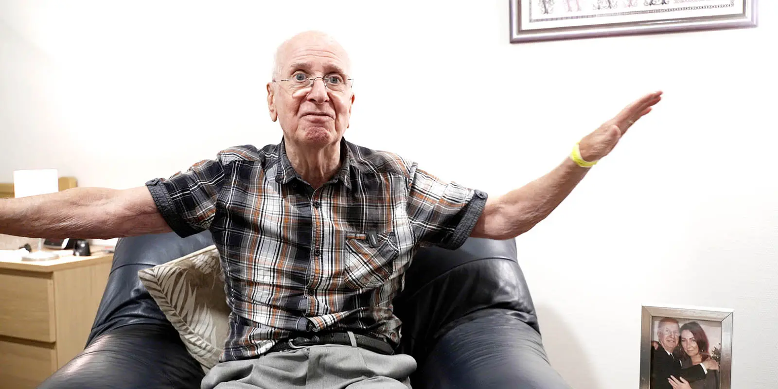 Bewoner met dementie heeft als hartenwens nog één keer vliegen. Op de foto zit hij op een stoel en spreidt hij zijn armen uit