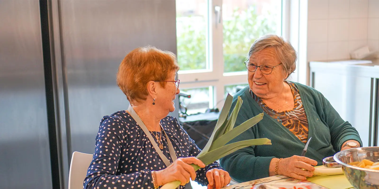 Bewoners van Het Rijssenbeekhuis helpen in de keuken de kok met groenten snijden voor de verse maaltijd. Ter illustratie bij de blog van locatiemanager Wendeline Roest-Lovers, over de bewoners die haar dag kleuren.