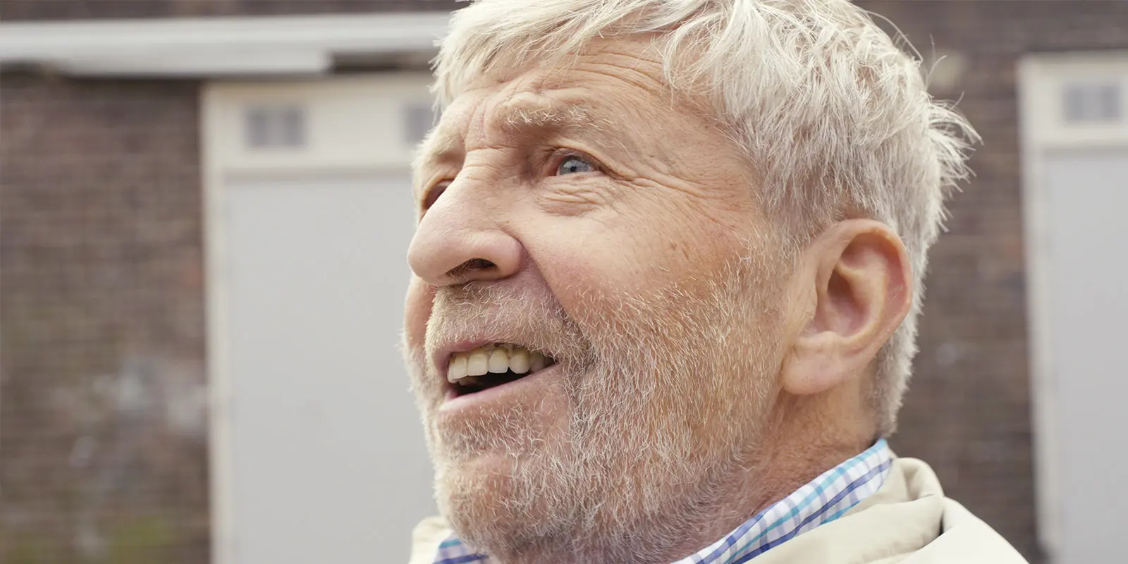 Jack, bewoner van Het Bondeijkehuis in Vlissingen, kijkt blij naar de zanger die voor hem zingt in Scheveningen, tijdens de vervulling van zijn hartenwens. Close-up.