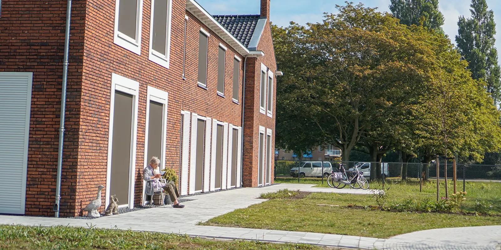 Een bewoner met dementie in de tuin van een woonzorglocatie van Dagelijks Leven. Ze zit in de zon met een domotica-hond op schoot. Ter illustratie bij blog van verpleegkundig specialist die vertelt over haar werk.