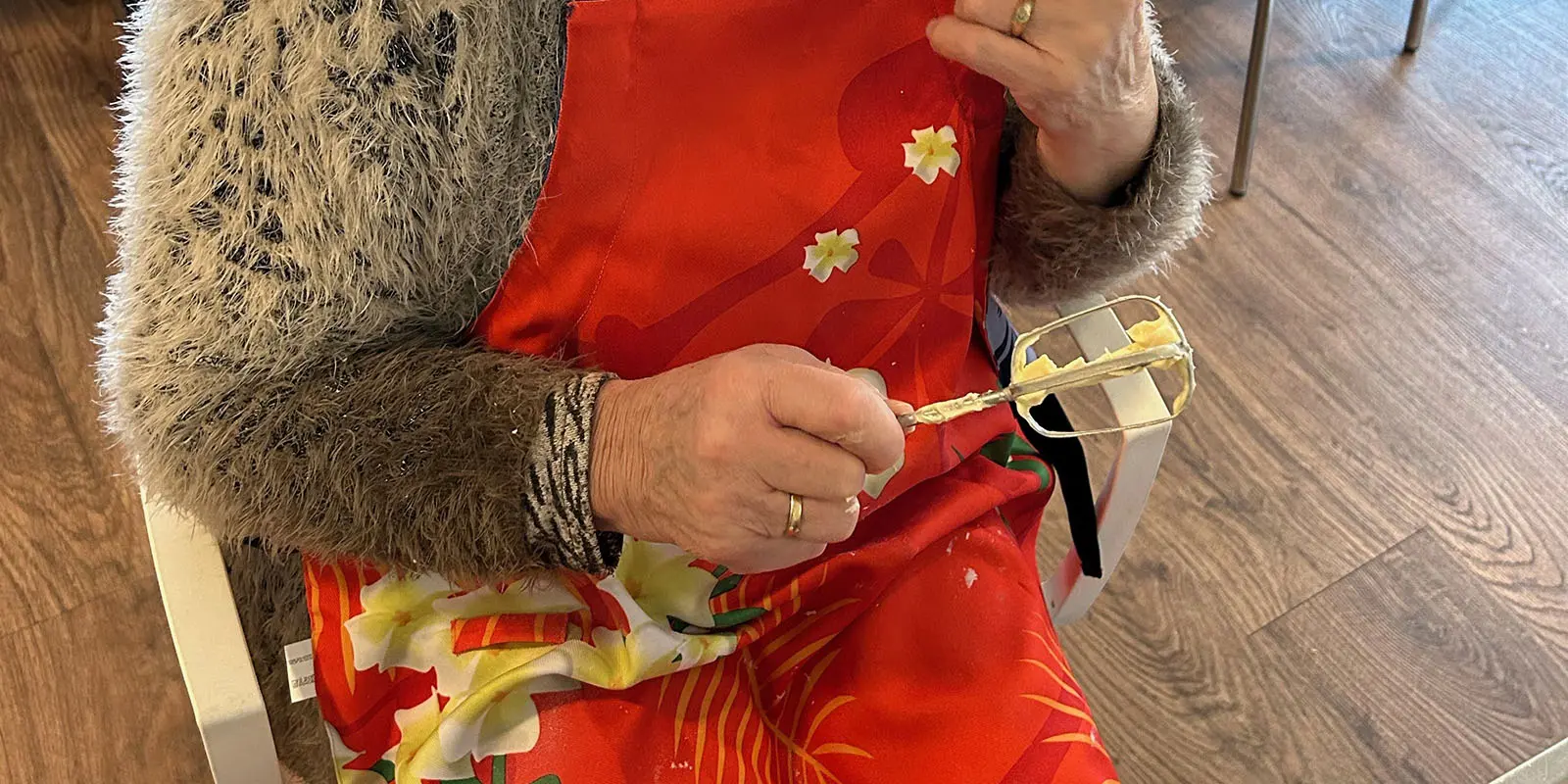 Een bewoonster met dementie snoept de garde met cakebeslag schoon.