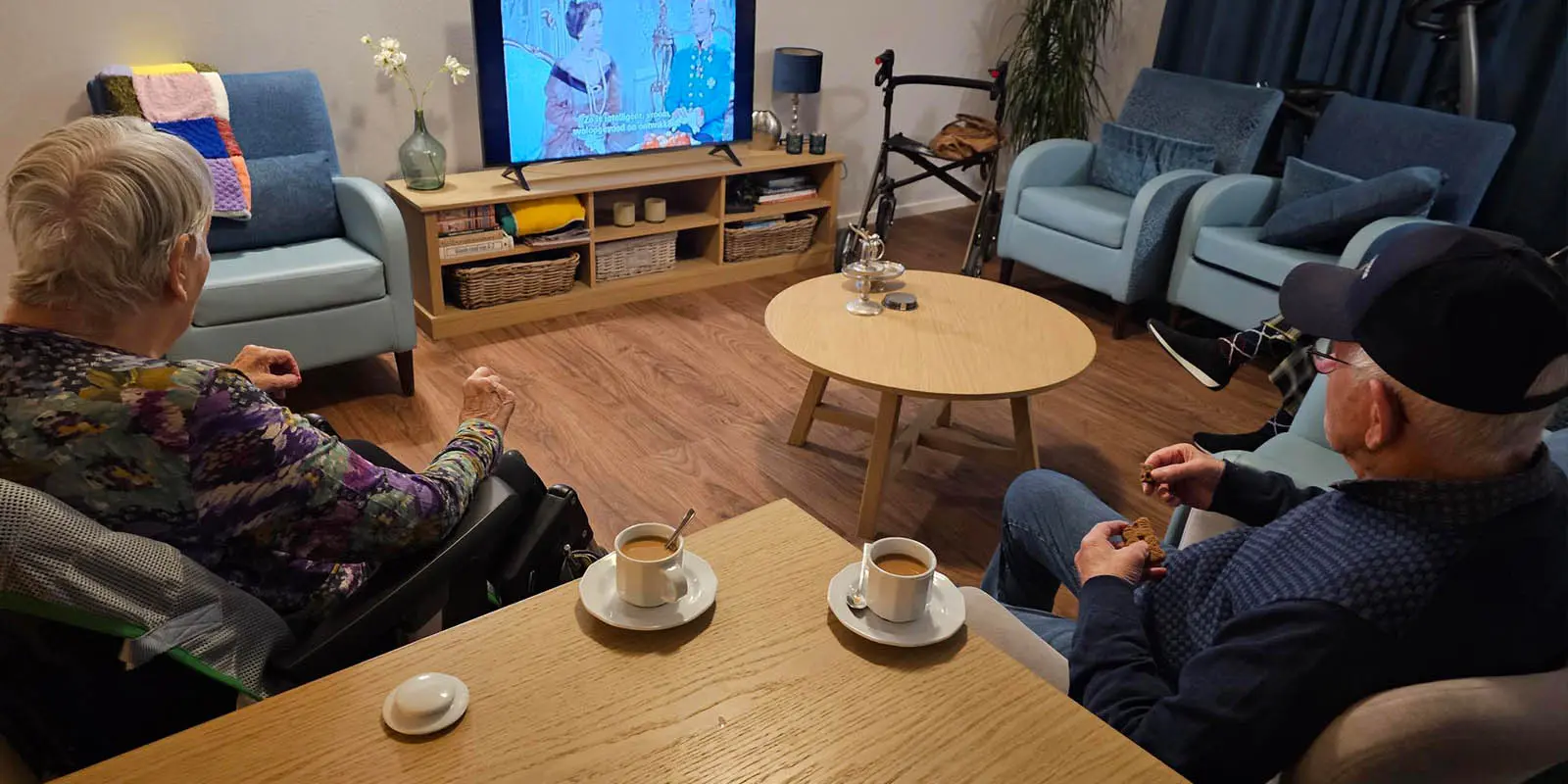 Kleine geluksmomentjes, die maken het werken in de dementiezorg zo bijzonder, vindt onze verzorgende IG. Op de foto twee bewoners op de rug gezien, die samen genieten van een televisieserie met ene kopje koffie.