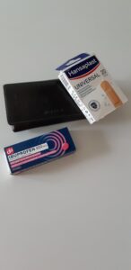 Foto van een portemonnee met een pakje ibuprofen en pleisters ernaast. Ter illustratie bij een anekdote over een dame met pijn in haar portemonnee. 