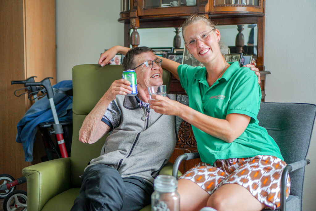 Een bewoonster met Alzheimer proost met een zorgmedewerker in het verzorgingshuis voor mensen met dementie van Dagelijks Leven