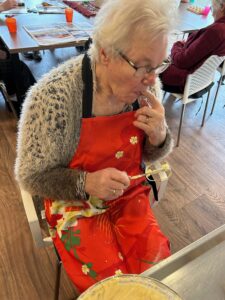 Een bewoonster met dementie snoept de garde met cakebeslag schoon.